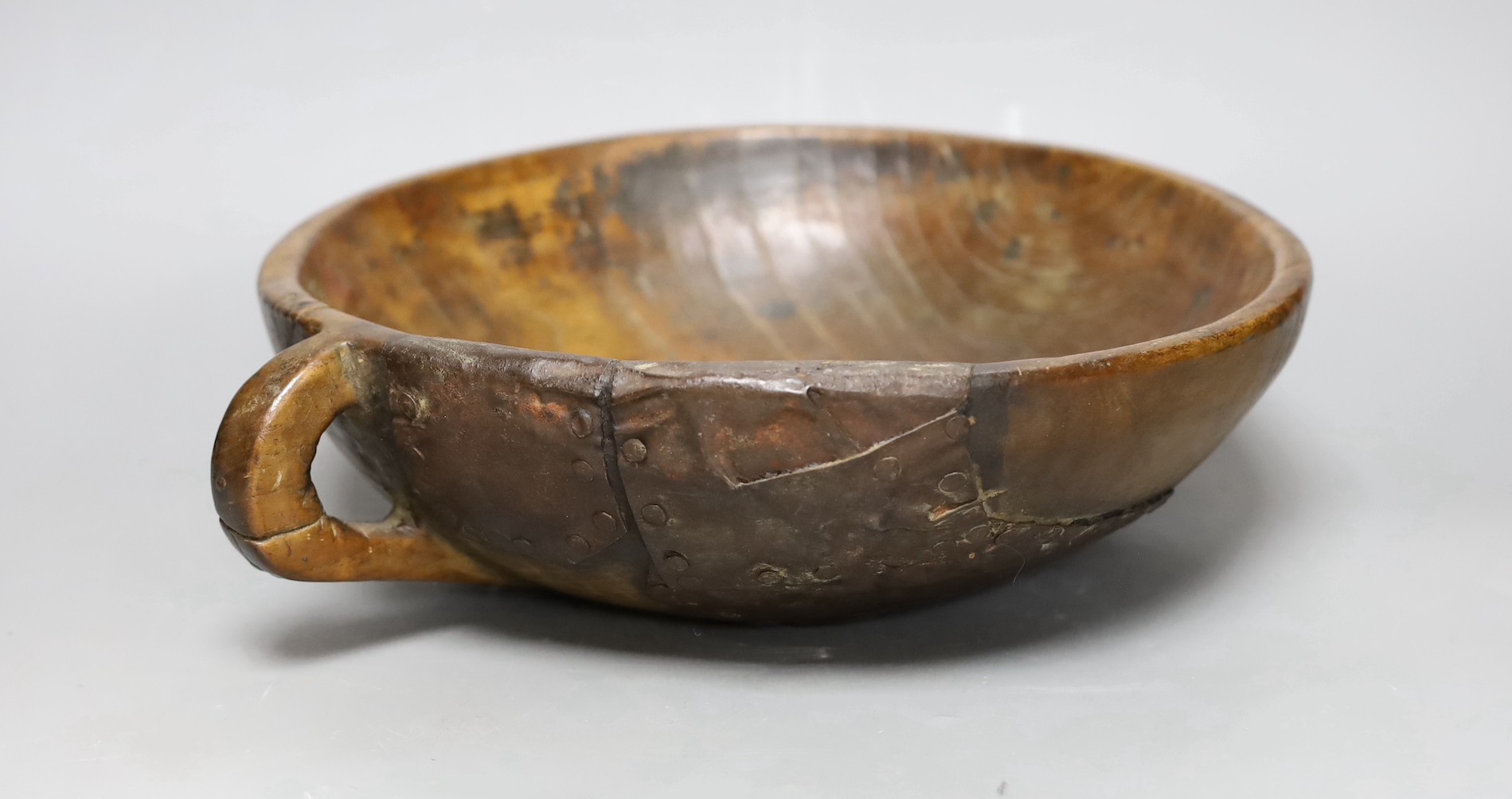 A carved elm mazer bowl, with old blacksmith repair, 31cm diameter